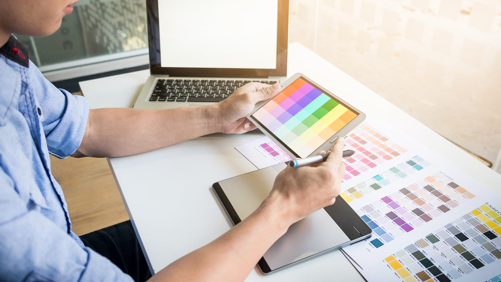 Un profesional con camisa azul revisa muestras de color en una tableta